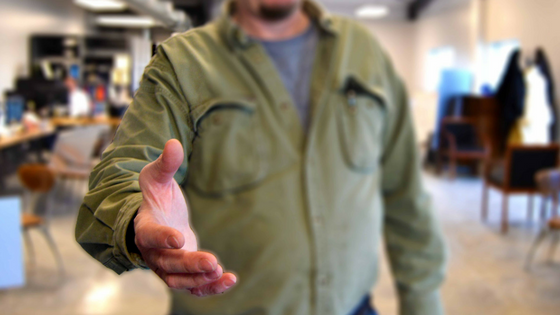 A man holds out his hand in preparation for a handshake.